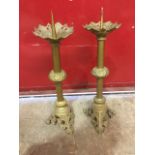 A pair of large Victorian gothic brass candle stands, the tubular columns supporting pierced leaf