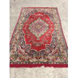 An oriental style rug woven with oval scalloped floral medallion in red field framed by conforming