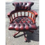 A reproduction leather button upholstered captains chair, with shaped backrest above rounded studded