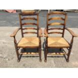 A pair of eighteenth century style oak ladderback armchairs, with shaped arms on baluster turned