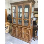 A glazed walnut cabinet with moulded cornice above a mirror-back cupboard with glass shelves and two