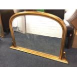 A Victorian style overmantle mirror, the arched bevelled plate in cushion moulded gilt frame, on