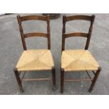 A pair of oak rush seated country chairs, with arched back rails on turned supports above tapering