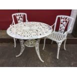 A circular garden table with a pair of matching chairs, the pieces with pierced floral decoration,