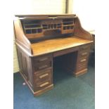 An Edwardian oak roll-top desk, the tambour enclosing a fitted interior with shelves, drawers and
