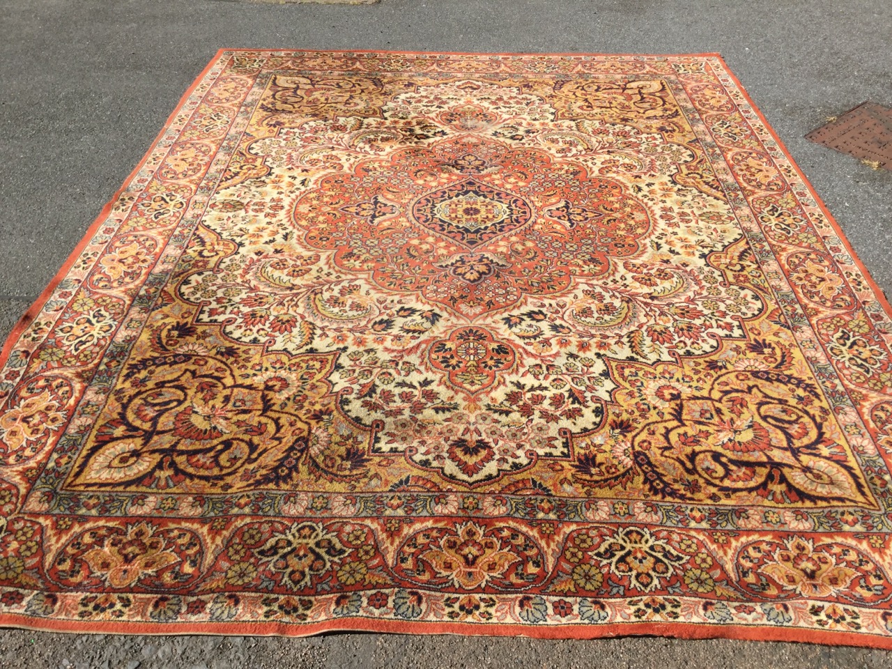 An oriental style Wilton carpet woven with scalloped central medallion on ivory field with golden