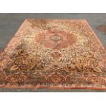 An oriental style Wilton carpet woven with scalloped central medallion on ivory field with golden