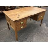 A panelled oak kneehole desk, the rectangular top above two slides and drawers mounted with brass