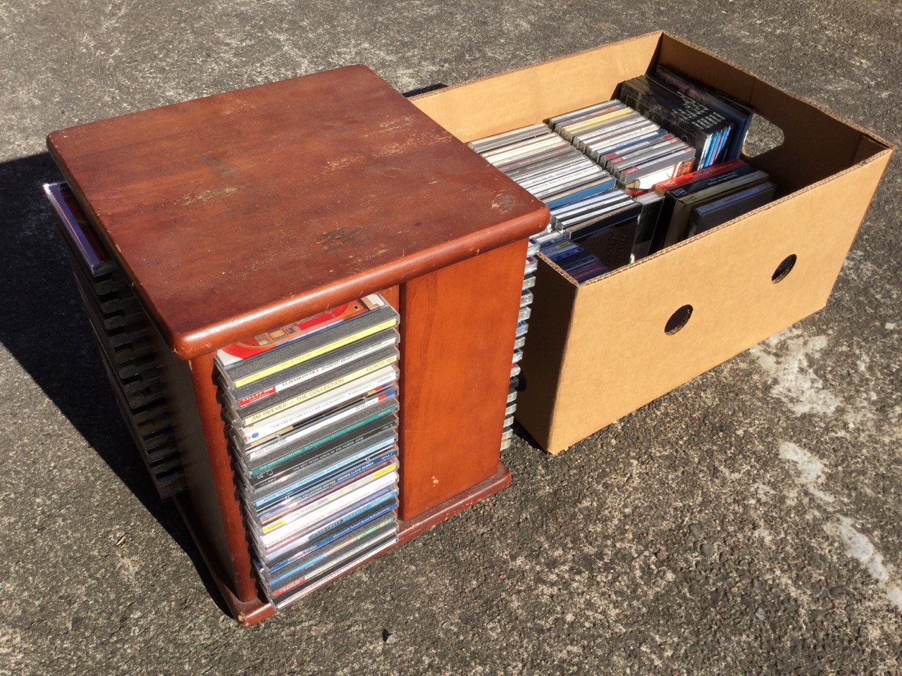 A revolving rack containing 64 CDs; and a box of approx 80 further CDs, casettes, etc. (A lot)