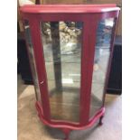 A painted display cabinet of scalloped outline having interior with two glass shelves and mirror