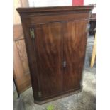 A nineteenth century mahogany corner cupboard with moulded cornice above a pair of boxwood strung