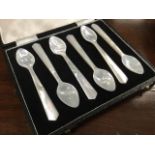 A cased set of six mother-of-pearl egg spoons with tapering handles and small pointed bowls -