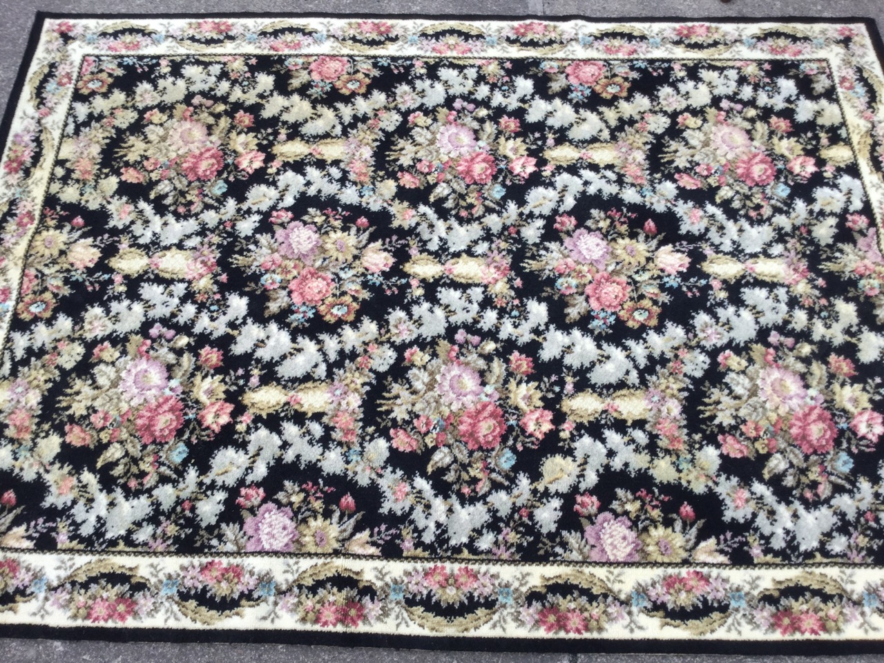 A Spanish Whitney wool rug woven in the Escorial pattern with field of flowers on black ground