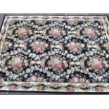 A Spanish Whitney wool rug woven in the Escorial pattern with field of flowers on black ground