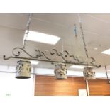 A hanging light fitting with three tubular copper shades cut & pierced with floral decoration, on