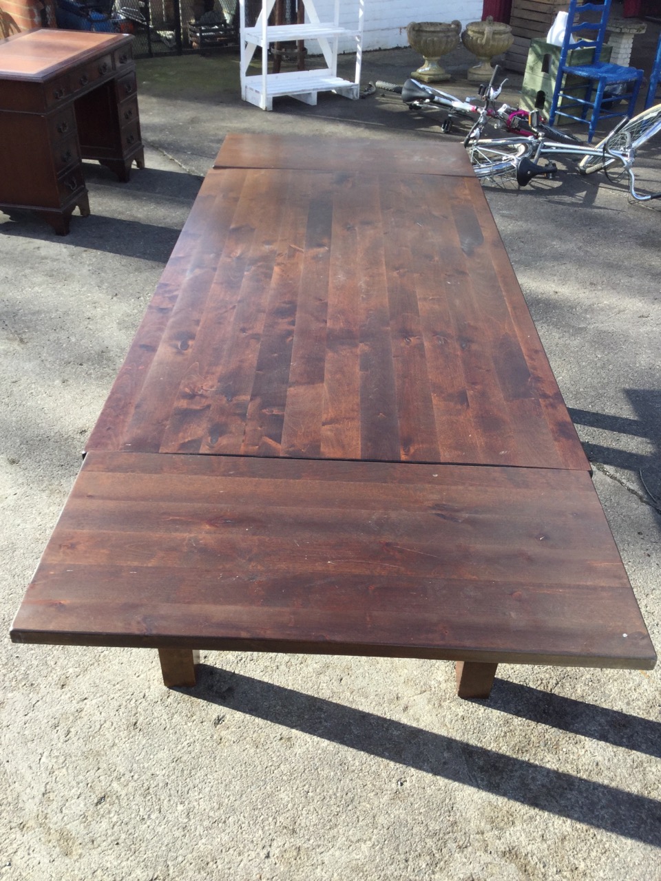 A rectangular hardwood dining table with two spare leaves, raised on square column legs. (95in x