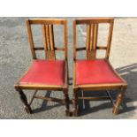 A pair of 1930s oak chairs with fluted splats above stylised carved roundel panels, the drop-in