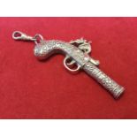 A working silver whistle modelled as a flintlock pistol, with foliate scrolled decoration, mounted
