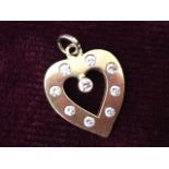 A 9ct gold pendant in the form of a heart, the open panel bezel set with nine diamonds, mounted with