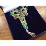 An art nouveau style enamelled silver pendant with three flowers on shaped pierced panel, having