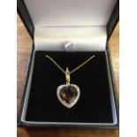 A 9 carat gold heart shaped pendant with claw set smokey quartz above a border of diamonds,