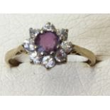 A 9ct gold ring having flowerhead setting with cenral claw set ruby framed by eight diamonds -