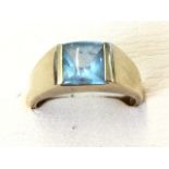 A 10ct gold signet ring set with square blue topaz stone, with wide tapering shoulders.