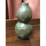 A bronze vase cast as a double gourd, embossed with circular yin & yang panels on scrolled