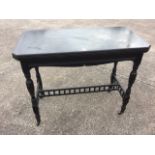 A late Victorian ebonised card table, the turn-over-top with canted corners above a shaped moulded