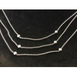 An 18ct white gold necklace, the three-strand chain each mounted with bezel set diamonds in bun