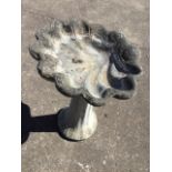 A composition stone birdbath, with shell shaped bowl on flared fluted column. (27in)
