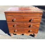 A Victorian mahogany chest of three long drawers mounted with knobs, above a shaped apron raised