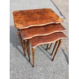 A nest of three burr walnut coffee tables, the moulded scalloped tops on slender tapering legs