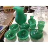 A suite of green overlay glass including a large pitcher with applied scrolled handle, vases, bowls,