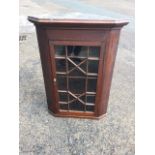 A nineteenth century oak corner cupboard with moulded ogee cornice above an astragal glazed door