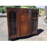 A walnut side cabinet, the bowfronted central section with panelled door flanked by arch shaped