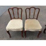 A pair of mahogany dining chairs with triple hoop backs above stuffover upholstered seats, raised on