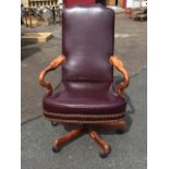 A leather upholstered office armchair with high back and brass studding, having crook arms above
