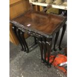 A nest of three mahogany tables with scalloped tray tops having chisel carved edges, raised on