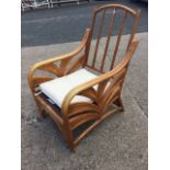 A contemporary cane armchair with arched back and curved arms framing palm style panels, the