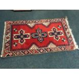 An oriental rug woven with three Maltese cross style medallions on madder field with stars, framed