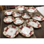 A Coalport 12-piece dessert service, decorated with polychrome floral bouquets in gilt scroll panels