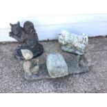 Three composition stone garden ornaments - a shaggy dog, a squirrel on an oval plinth, and two