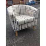 A contemporary upholstered armchair with rounded back above a loose cushion seat, raised on turned