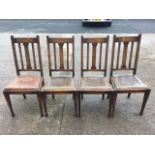 A set of four Edwardian oak dining chairs with slatbacks above drop-in rexine seats, raised on