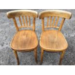 A pair of Polish beech bentwood chairs, with curved slatbacks above rounded seats, raised on