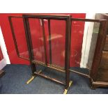 A nineteenth century mahogany firescreen, with glass panels, the two sideways sliding glazed