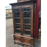 A George VI oak bookcase with overhanging moulded cornice above a fluted scroll carved frieze, the