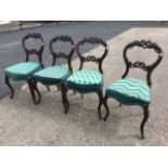 A set of four Victorian mahogany balloon-back dining chairs, having pierced scrolled carving to