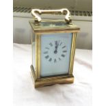 A brass carriage clock, the architectural style case with reeded cornerposts, having enamelled